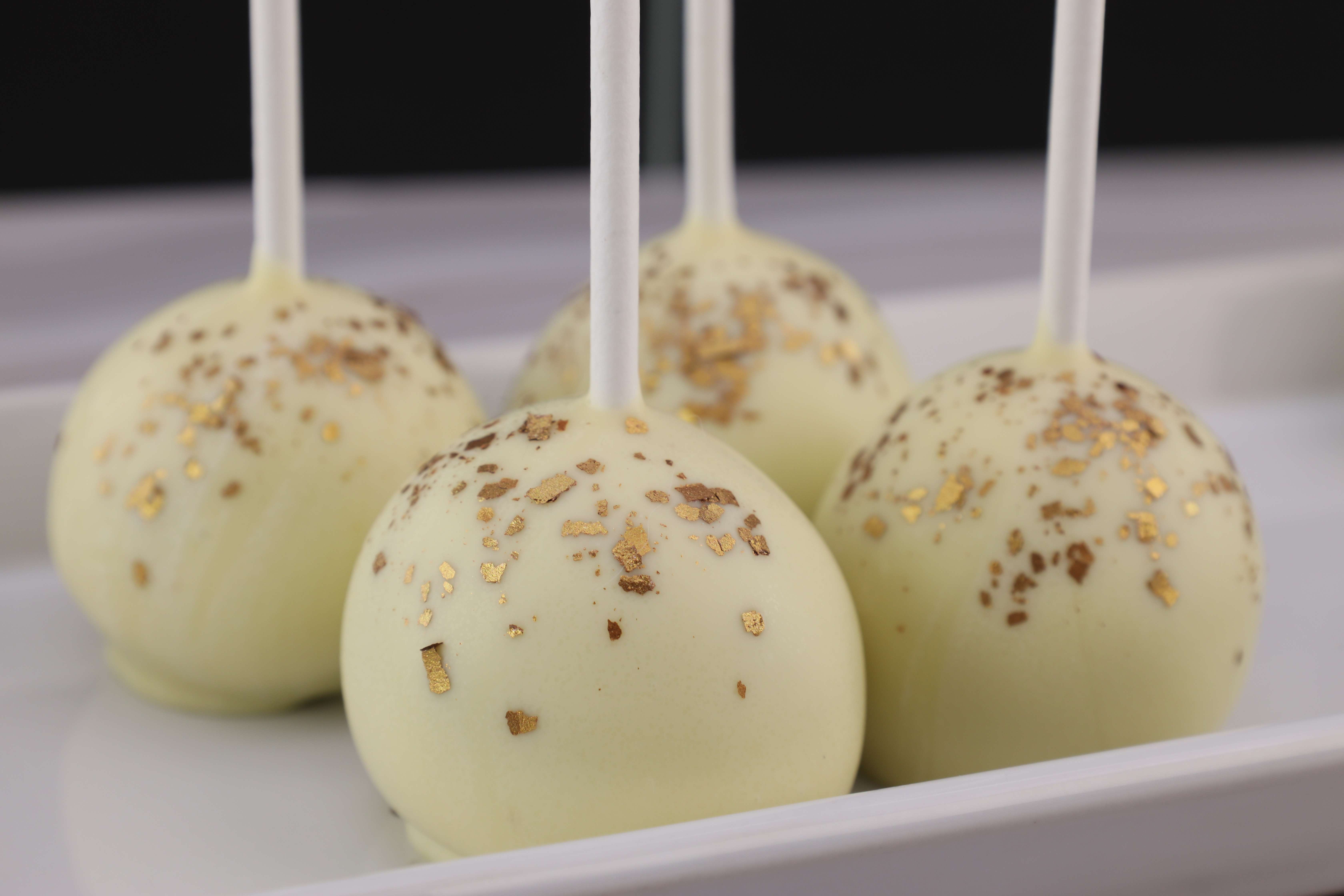 Leckere Cake Pops mit weißer Schokolade überzogen und mit essbarem Goldglitter verziert. 