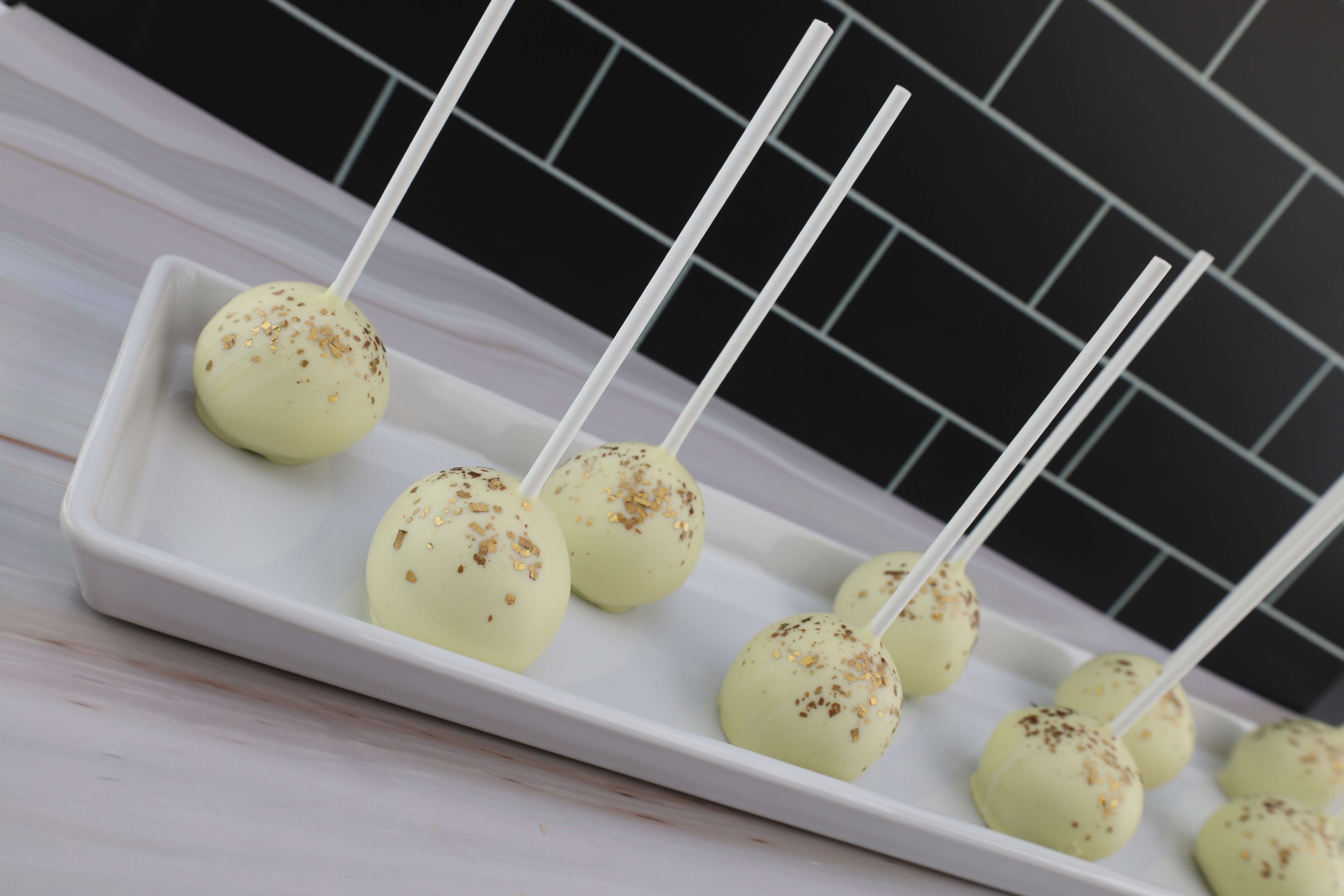 Leckere Cake Pops mit weißer Schokolade überzogen und mit essbarem Goldglitter verziert. 