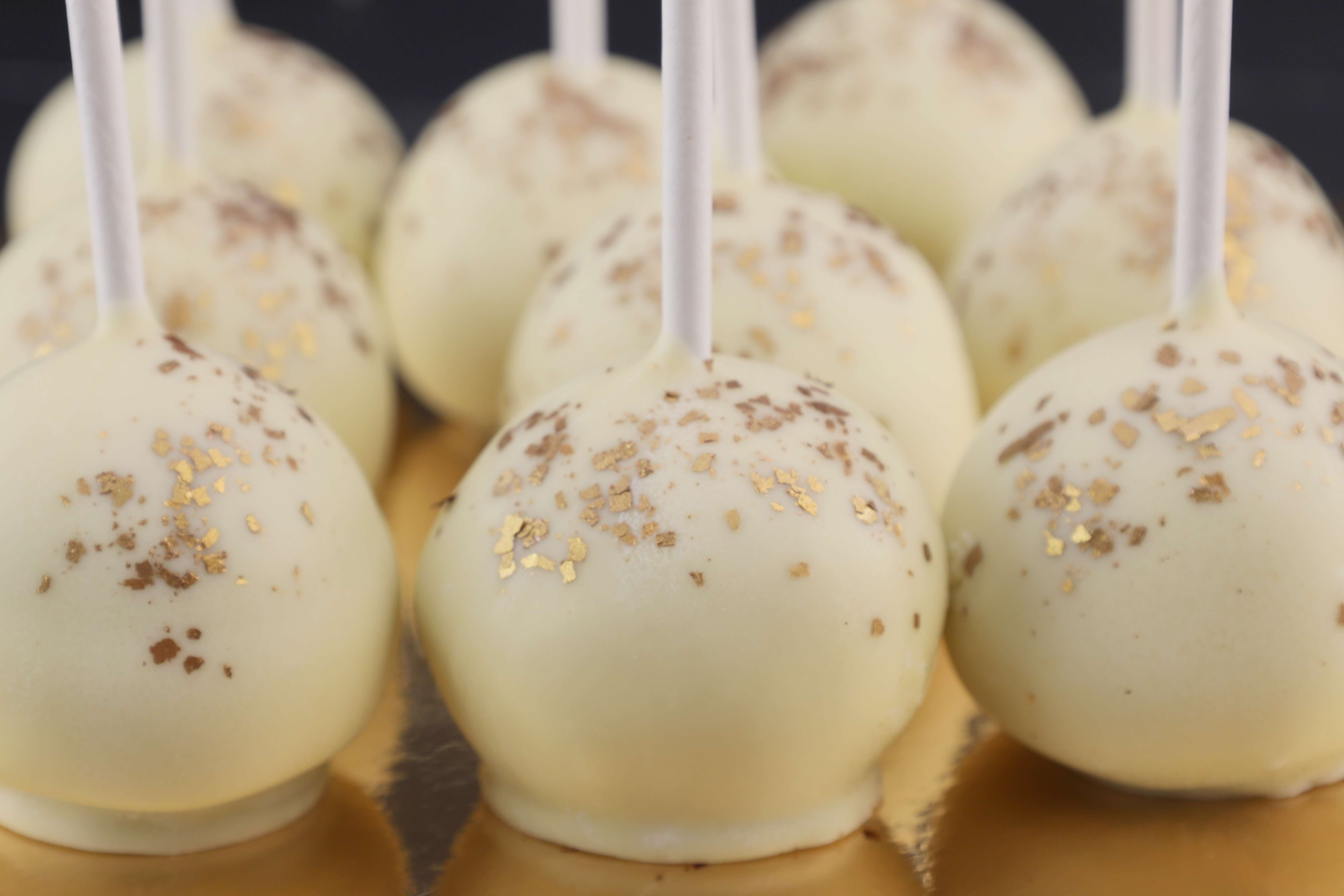 Leckere Cake Pops mit weißer Schokolade überzogen und mit essbarem Goldglitter verziert. 